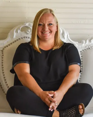 Portrait of Becca Heidel, seated on a white studded couch