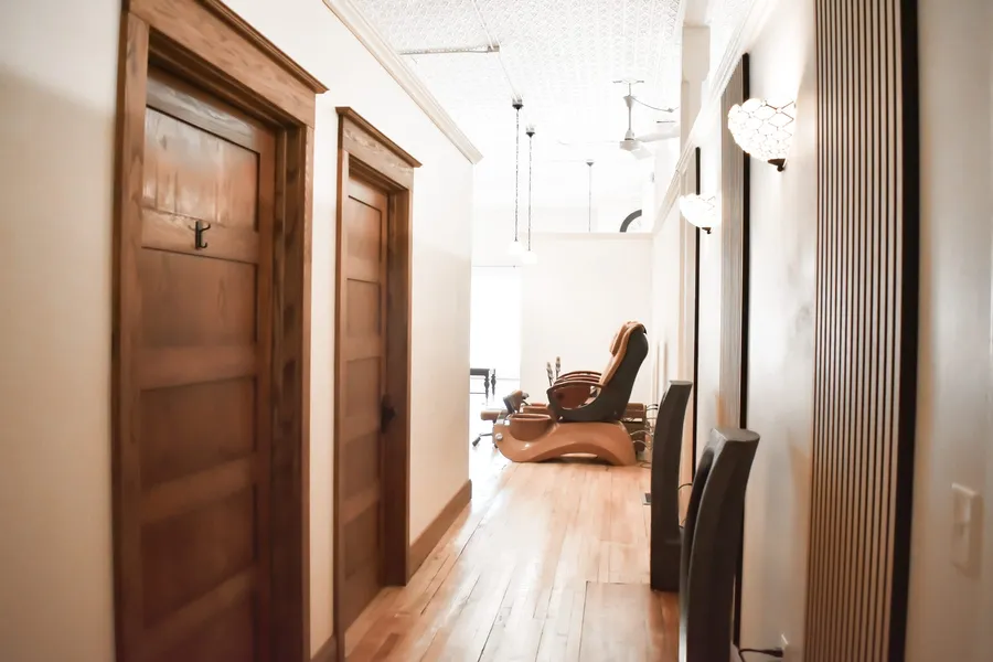 Hallway with wooden doors along the left, leading toward the pedicure chairs