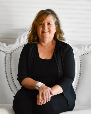 Portrait of Laura Anderson, seated on a white studded couch