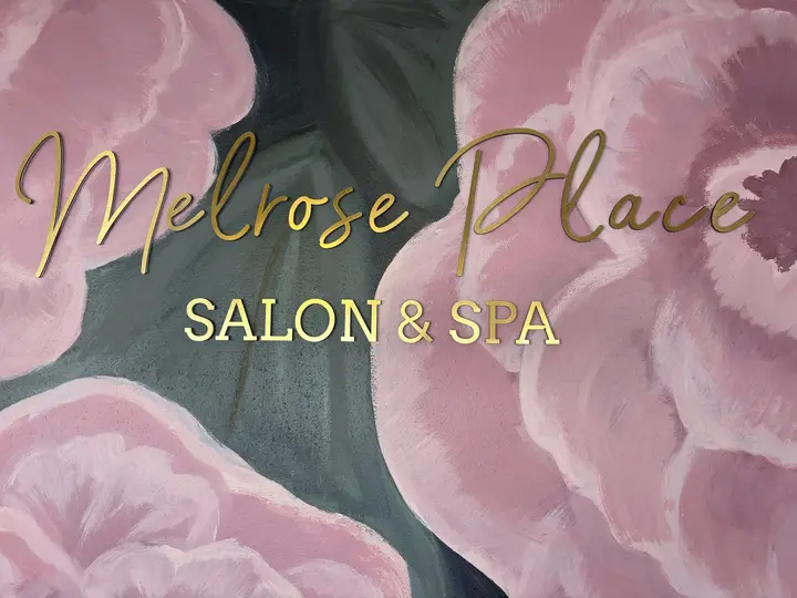 Gold Melrose Place Salon & Spa lettering on a hand-painted mural of pink peonies