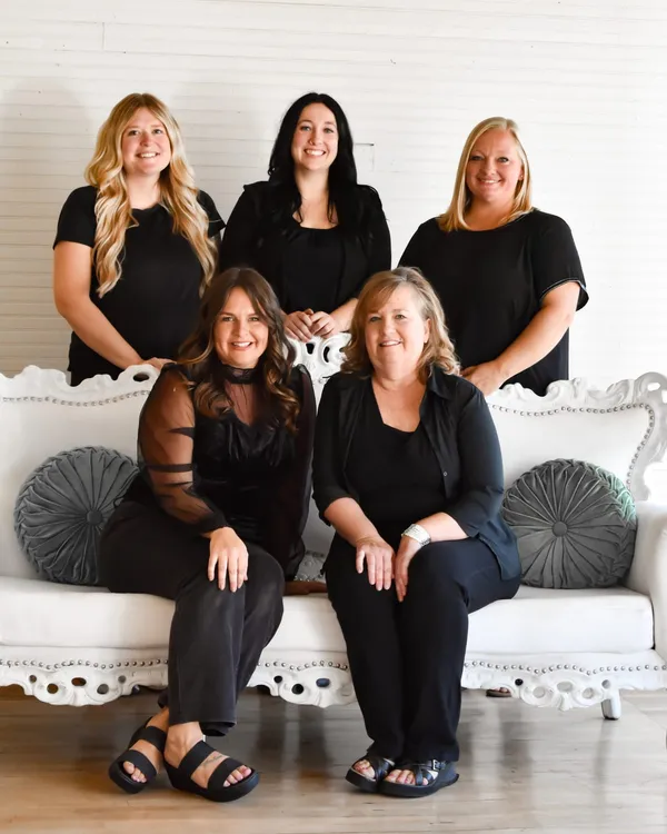 The five providers posed on a white ornate couch, three standing behind and two seated in front