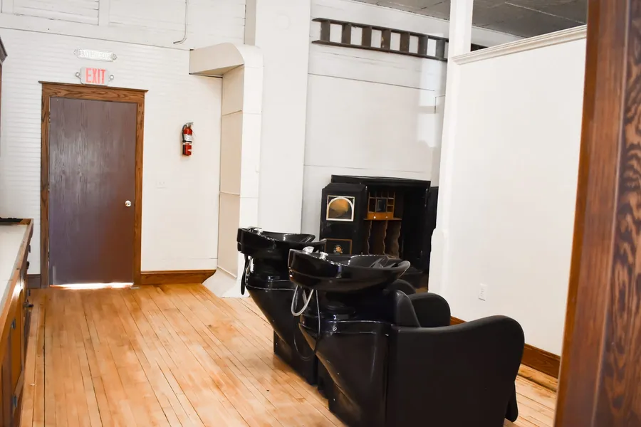 Two black shampoo chairs with wash bowls in the salon's wash area